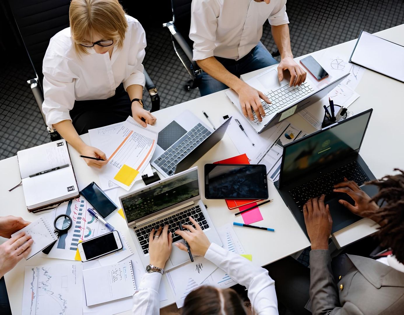 Geschäftsleute arbeiten an Laptops an einem Tisch.