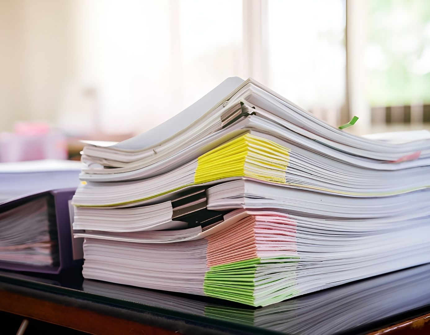 Ein Stapel Papiere liegt ordentlich auf einem Schreibtisch.